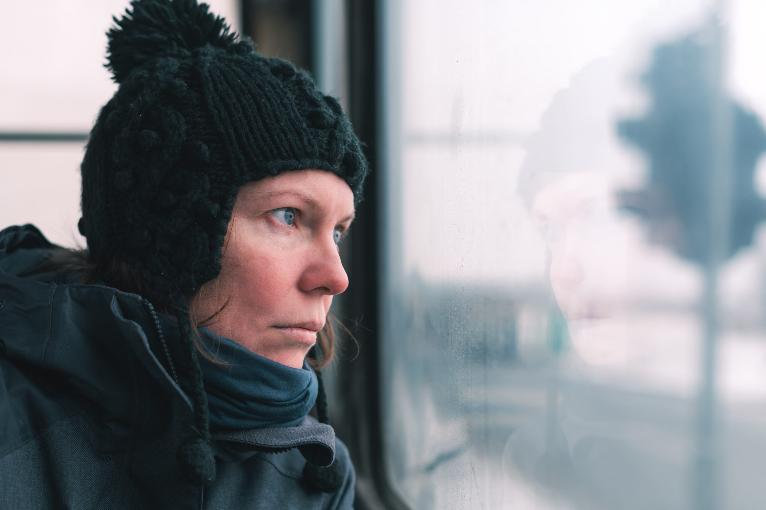 Mulher triste no ônibus olhando através da janela para a estrada em um dia frio de inverno