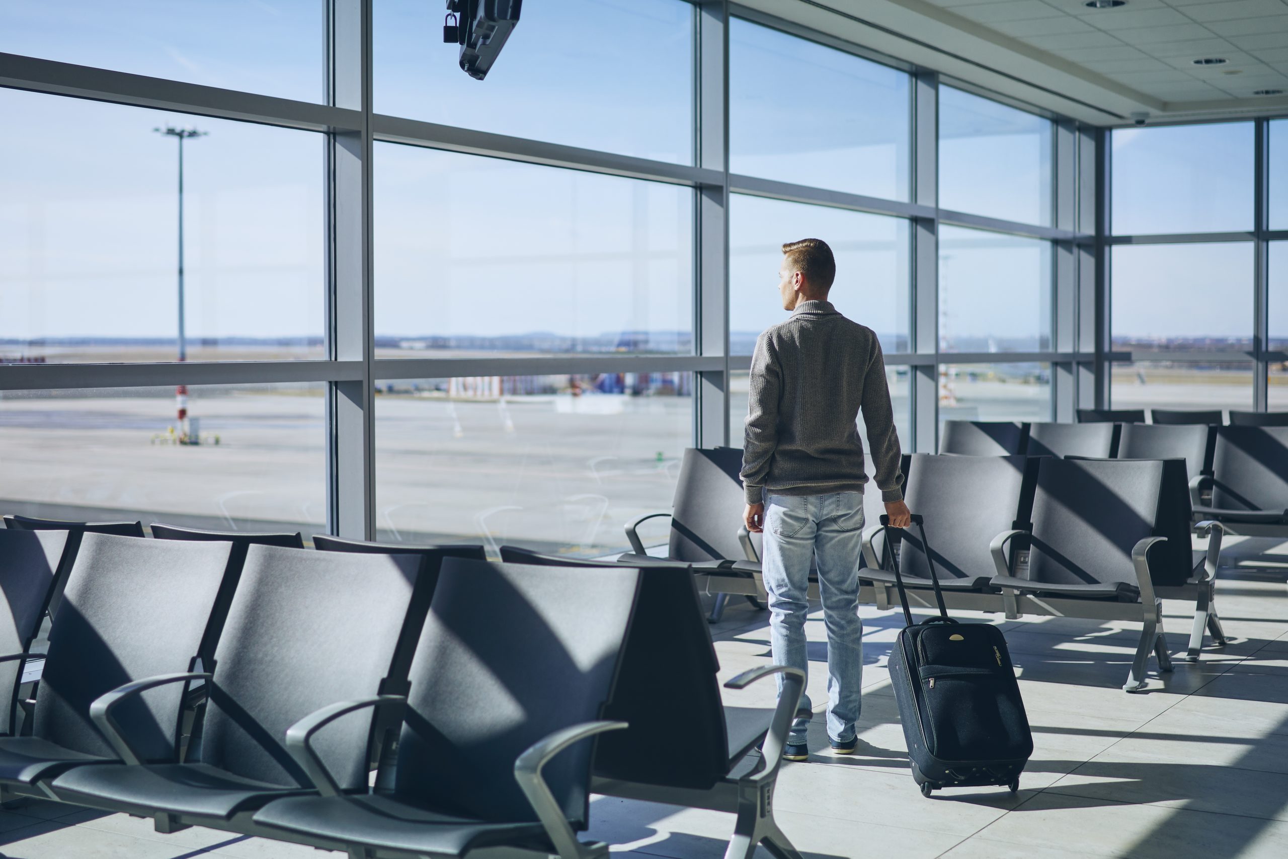 Uma pessoa que está voltando para casa olha, no terminal do aeroporto, com apreensão para o que está por vim