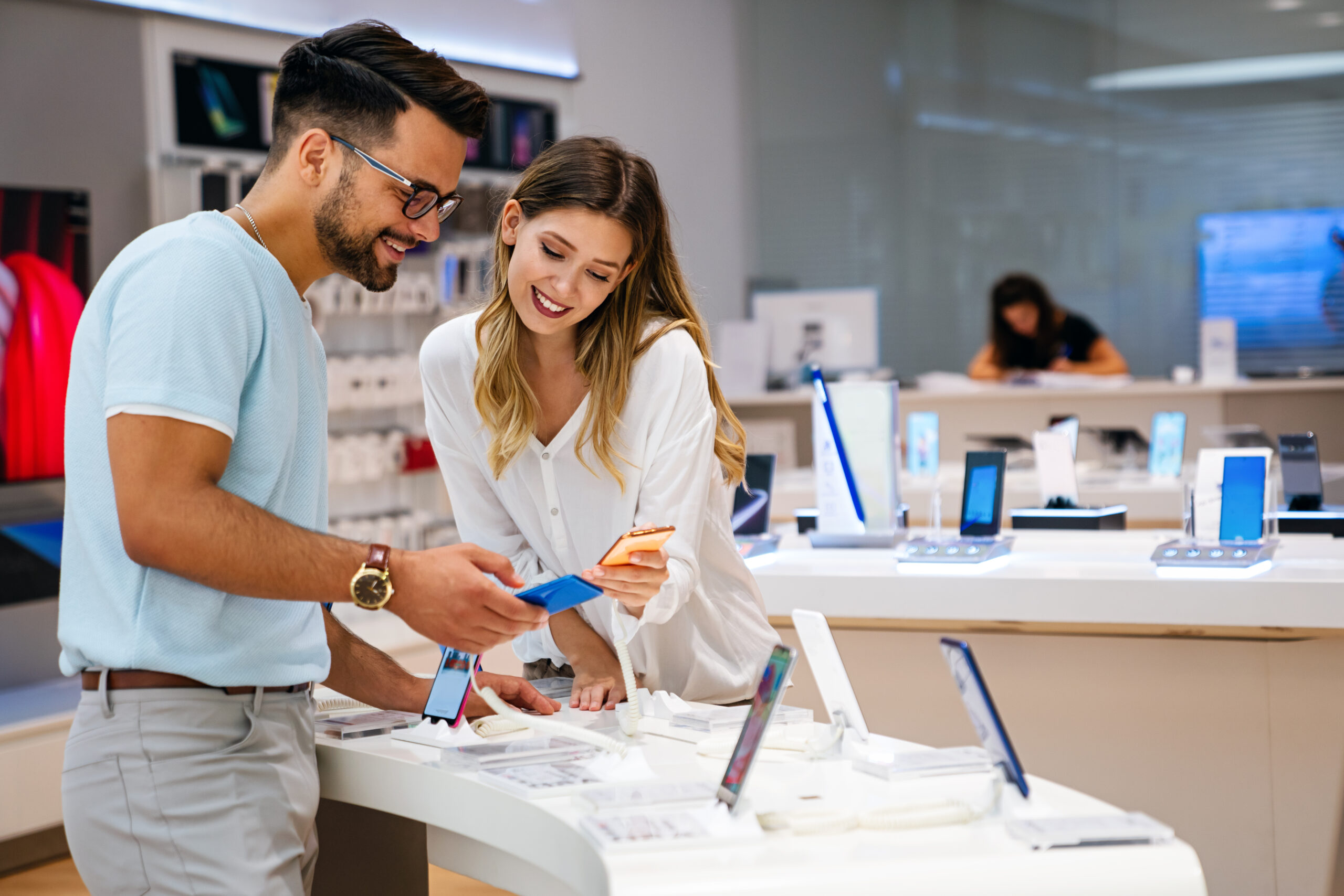 Um casal jovem em uma loja de telefones analisando um telefone para comprar